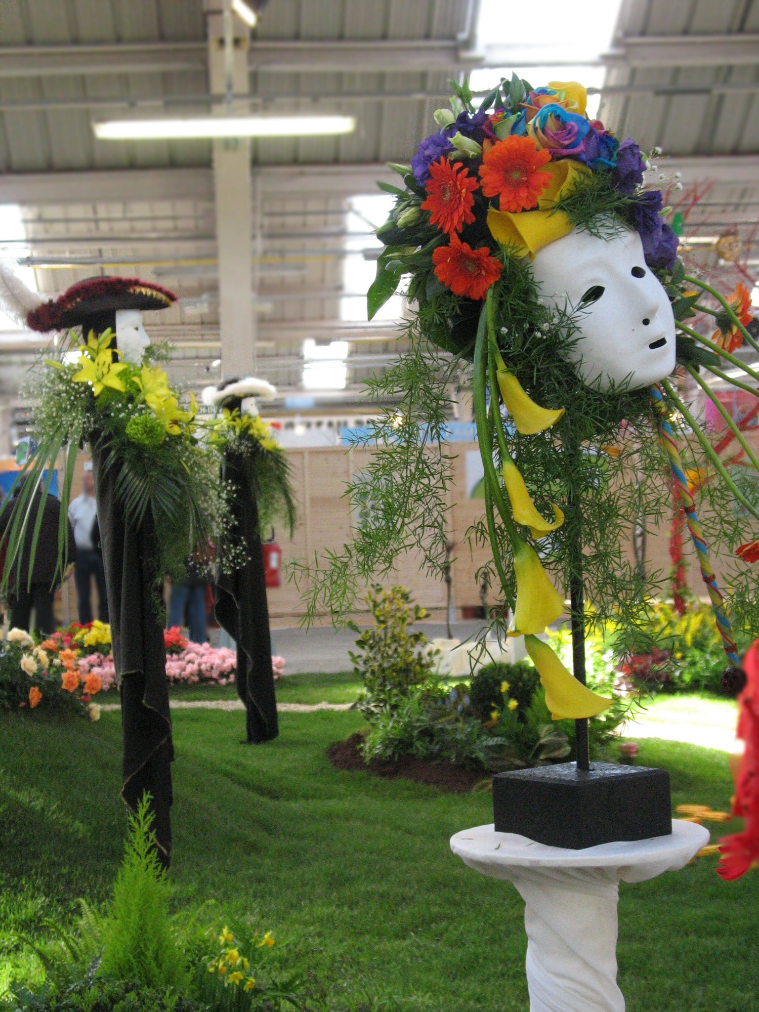 une tête blanche de carnaval coiffée de fleurs rouges bleues et jaunes