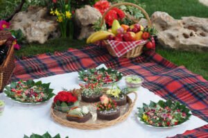 un pique nique fait de fleurs et feuilles à dominante rouge posé sur le sol recouvert d'une nappe à carreaux rouge