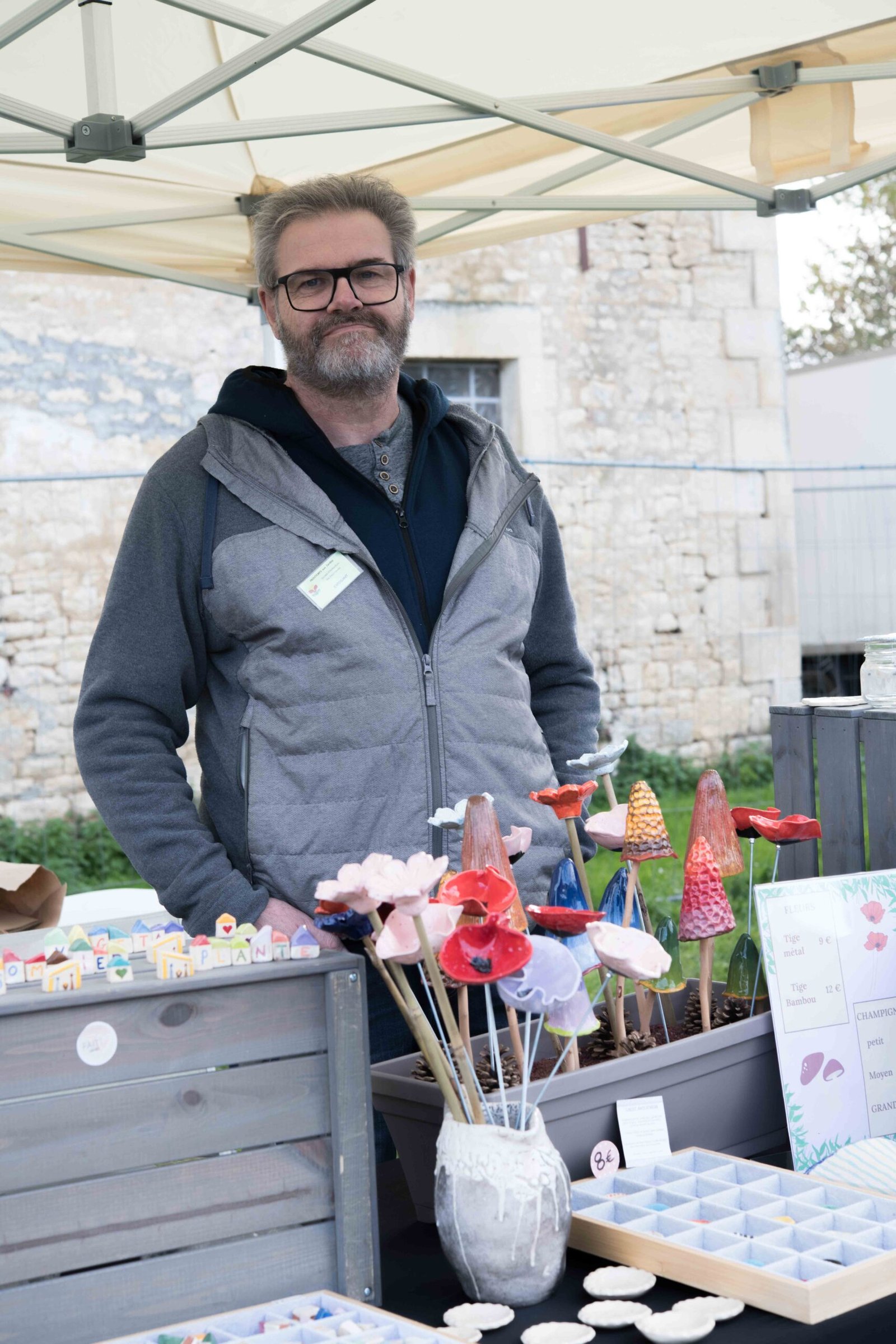 artisan devant son stand d'objets en céramique colorée